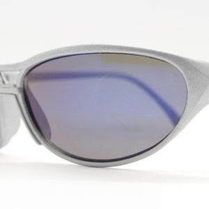 May include: Silver-toned sunglasses with a blue mirrored lens. The sunglasses have a curved, wraparound design.