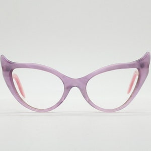 May include: Purple cat-eye glasses with pink accents. The glasses have a clear lens.