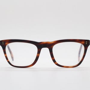 May include: A pair of eyeglasses with a tortoiseshell pattern frame. The glasses have a classic, rectangular shape with rounded edges and clear lenses. The frame is a mix of brown and amber tones.