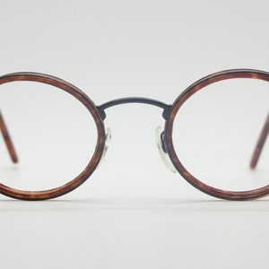May include: A pair of round, tortoiseshell eyeglasses with black metal arms.