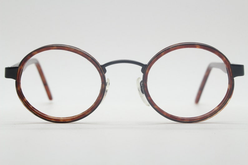 May include: A pair of round, tortoiseshell eyeglasses with black metal arms.