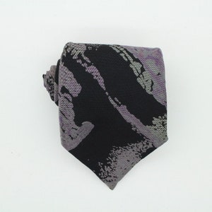 Könnte beinhalten: Eine schwarze und graue gemusterte Krawatte mit abstraktem Design.