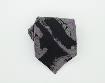 Puede incluir: Una corbata de patrón negro y gris con un diseño abstracto.