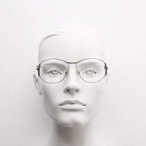 Puede incluir: Una cabeza de maniqu&iacute; blanca que lleva unas gafas finas de montura met&aacute;lica de forma rectangular.