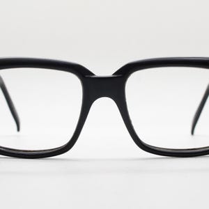 May include: Black plastic framed eyeglasses with square lenses.