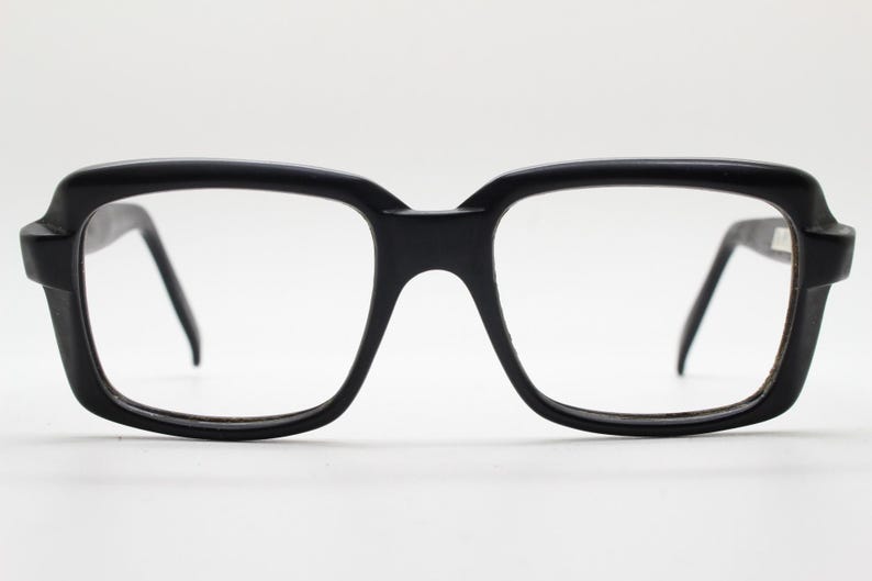 May include: Black plastic framed eyeglasses with square lenses.