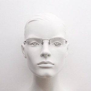 May include: A silver-toned metal frame with clear lenses. The frame has a subtle curve and the lenses are marked with the word "BOSS" in the right lens.