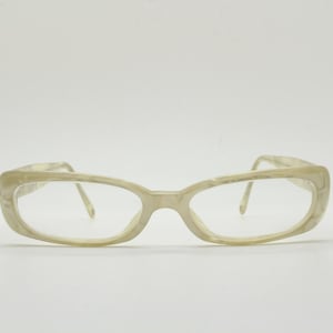 May include: A pair of vintage eyeglasses with a light beige, marbled frame. The rectangular frames have rounded edges and are connected by thin, gold-colored arms. The lenses are clear, and the glasses are set against a white background.