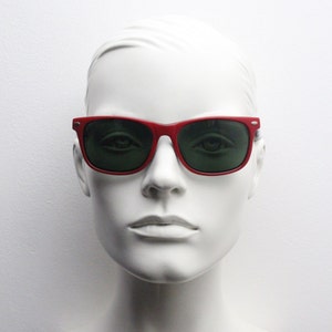 May include: A white mannequin head wearing red sunglasses with green lenses.