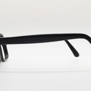 May include: Black plastic framed eyeglasses with a simple design. The glasses have a rectangular shape and are made of a lightweight material.