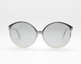 Vintage dameszonnebril uit de jaren 70. Glamoureus slank oversized grijs montuur met lichtgekleurde glazen.