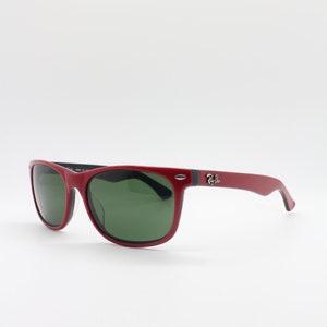 May include: Red sunglasses with green lenses and black accents. The sunglasses have a Ray-Ban logo on the side.
