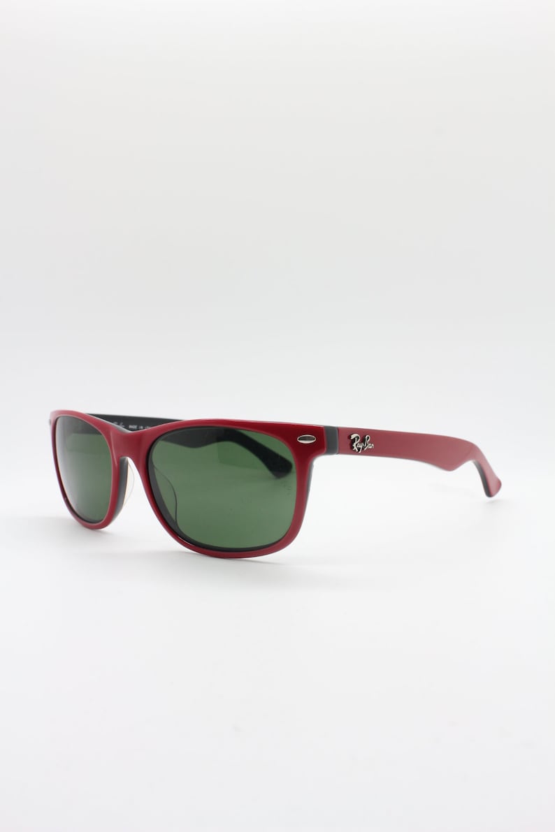 May include: Red sunglasses with green lenses and black accents. The sunglasses have a Ray-Ban logo on the side.