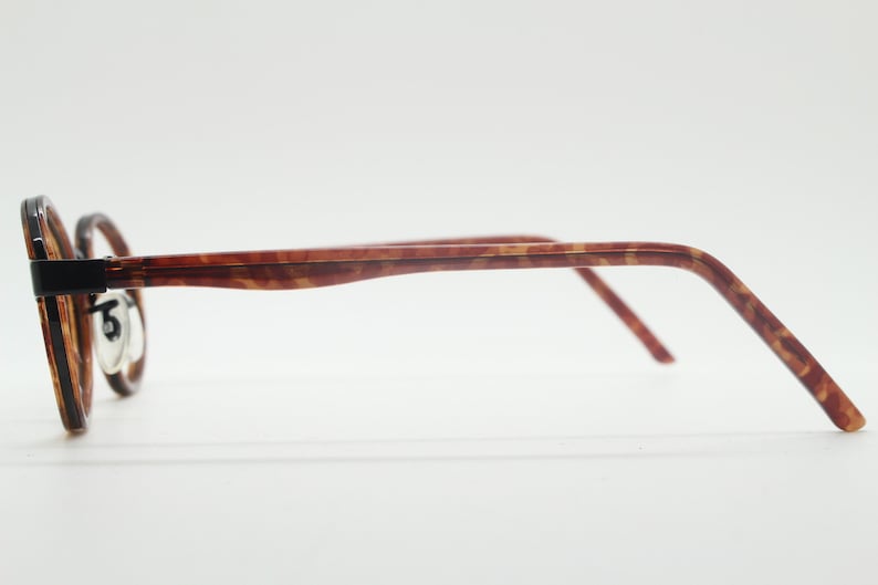 May include: A pair of tortoiseshell spectacles with black accents on the frame.