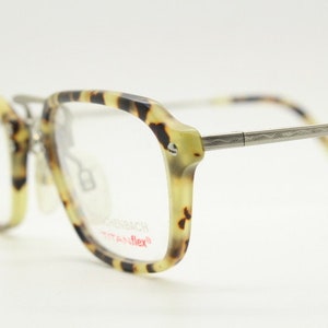 May include: Eyeglasses with a tortoiseshell pattern on the frames and temples. The frames are a mix of light brown, yellow, and dark brown. The temples are silver-colored metal. The lenses are clear.