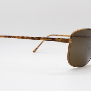 May include: Brown tortoise shell and gold metal aviator sunglasses with brown lenses.