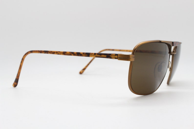 May include: Brown tortoise shell and gold metal aviator sunglasses with brown lenses.