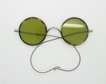 30s vintage round antique sunglasses by Willson. Metal frame encasing tortoise surrounds with green glass lenses and coiled arms. Windsor