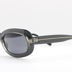 May include: Black oval-shaped sunglasses with a silver metal bridge and arms.