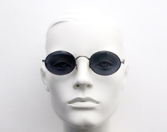May include: A white mannequin wearing round, black framed sunglasses with dark lenses.