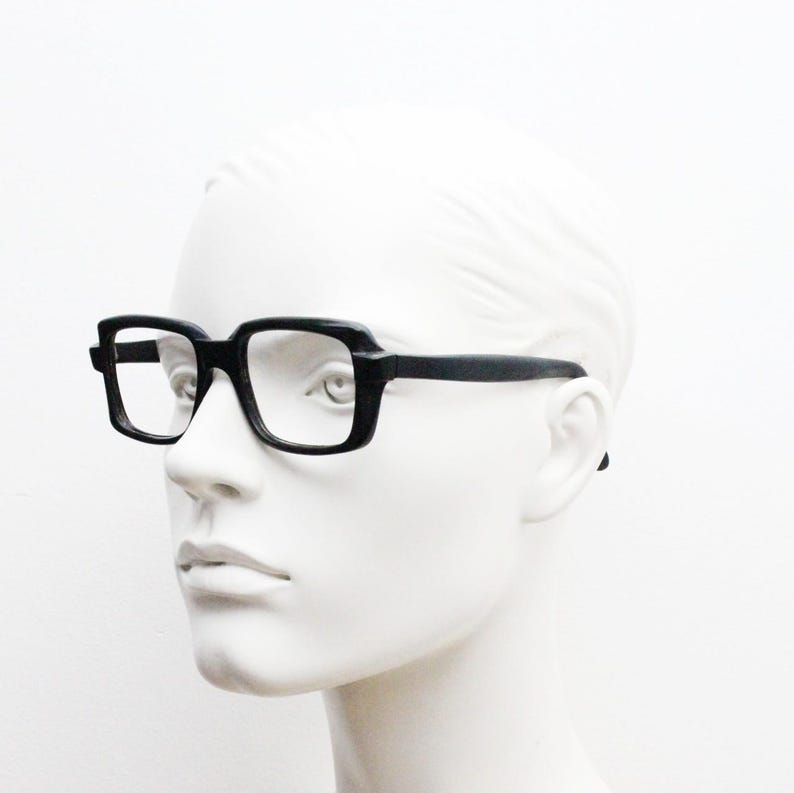 May include: Black rectangular eyeglasses with a thick frame and clear lenses.