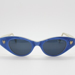Op de afbeelding: Blauwe cat-eye zonnebril met een wit montuur en gouden hart accenten. De zonnebril heeft een "Fendi Italia" label op de rechter lens.