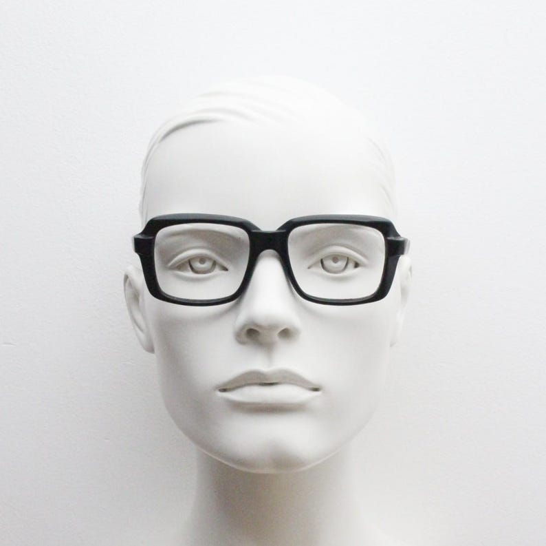 May include: A black plastic frame with rectangular lenses. The glasses are on a white mannequin head.