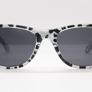 May include: Black and white patterned sunglasses with dark gray lenses.