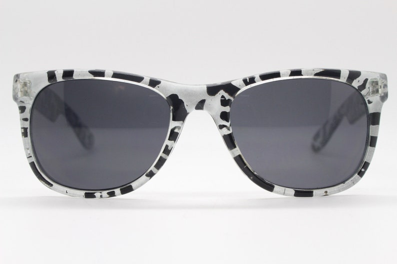 May include: Black and white patterned sunglasses with dark gray lenses.