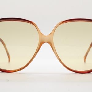 Op de afbeelding: Oversized vintage zonnebril met een bruin schildpadmontuur en lichtgele glazen. De bril heeft een kenmerkende vlindervorm, met een brug en pootjes in een lichtere bruintint. Een klassiek retro-accessoire.