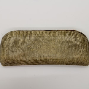 May include: A rectangular, olive-green eyeglasses case with a textured, scale-like pattern. The case has a curved top and a slightly darker border. The case is made of a durable material and is designed to protect eyewear.