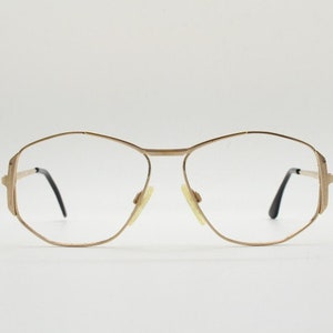 Puede incluir: Gafas de metal dorado con montura geom&eacute;trica y lentes transparentes.