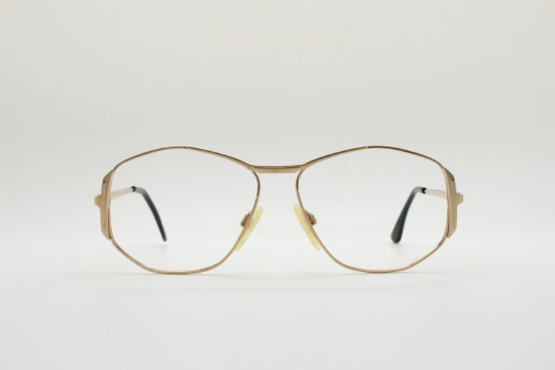 Puede incluir: Gafas de metal dorado con montura geom&eacute;trica y lentes transparentes.