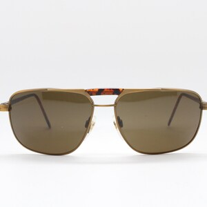 May include: Gold-tone aviator sunglasses with brown lenses and a tortoise shell bridge.