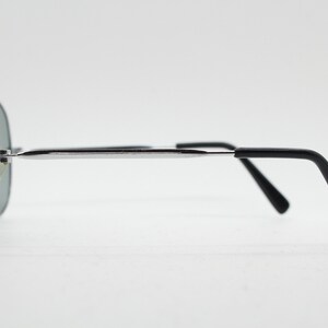 May include: Silver aviator sunglasses with black arms. The sunglasses have a mirrored lens.