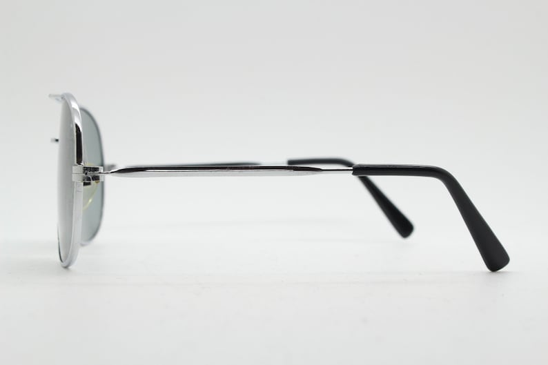 May include: Silver aviator sunglasses with black arms. The sunglasses have a mirrored lens.