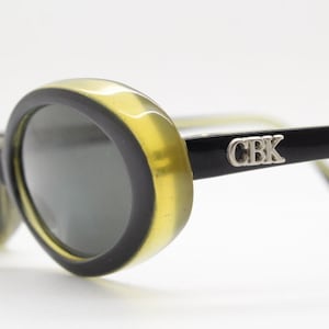 Caroline B.K. 90s Vintage oval sunglasses model 4059 made in Italy. Classic 60s design in thick black layered acetate with yellow base. NOS