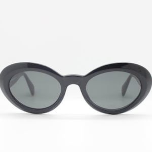 90s vintage sunglasses. NOS made in Italy. Medium sized womans 60s style oval cat eye in jet black with dark grey lenses. BNWT.  Mod