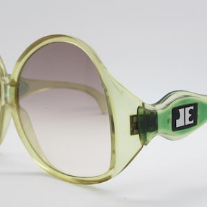Jacques Esterel vintage 70s sunglasses made in France. Era defining women&#39;s oversized round transparent crystal green frame with big logo&#39;s