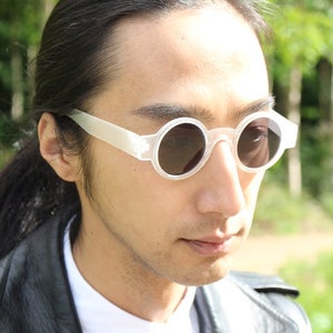 May include: White round sunglasses with a translucent frame.