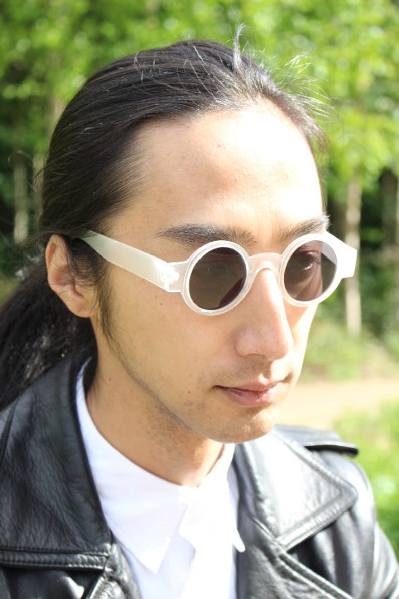 May include: White round sunglasses with a translucent frame.
