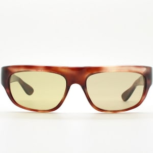 May include: Tortoise shell sunglasses with brown frames and yellow lenses.