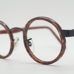 May include: Round tortoiseshell eyeglasses with black metal frames.