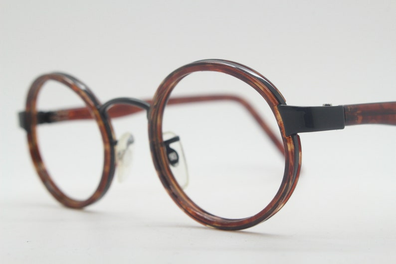 May include: Round tortoiseshell eyeglasses with black metal frames.