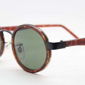 90s vintage oval sunglasses. NOS black metal frame encasing tortoise insert with green lenses. BNWT