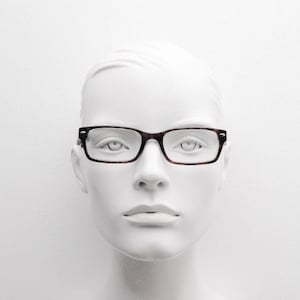 May include: A white mannequin head wearing brown tortoiseshell glasses with a rectangular frame.