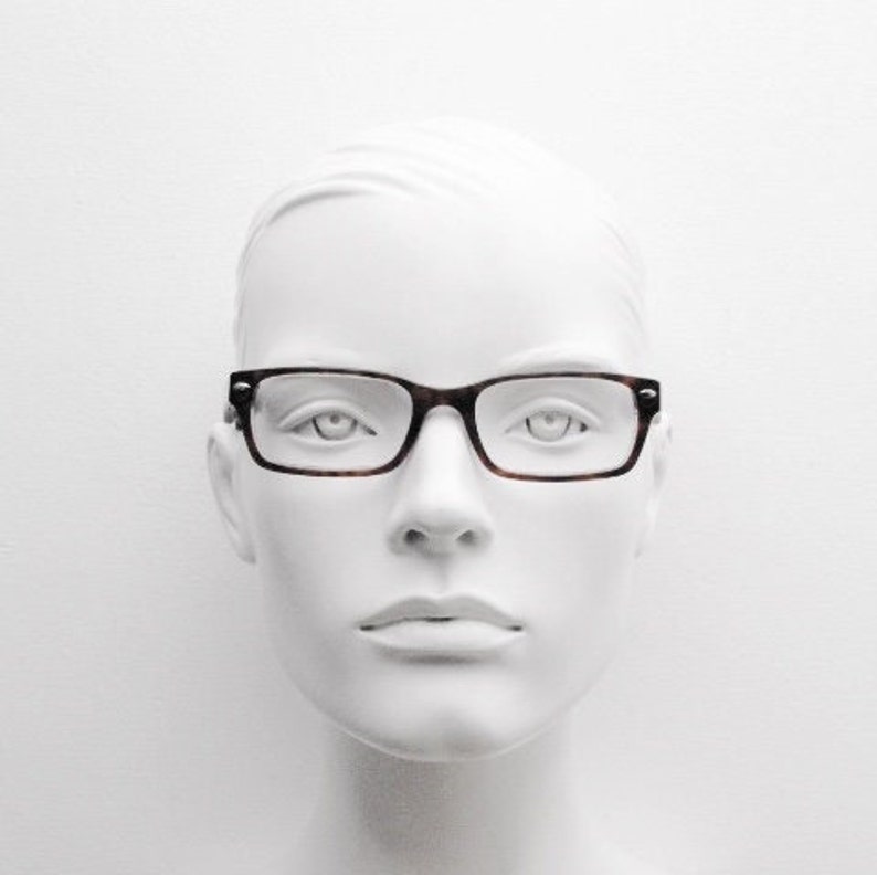 May include: A white mannequin head wearing brown tortoiseshell glasses with a rectangular frame.