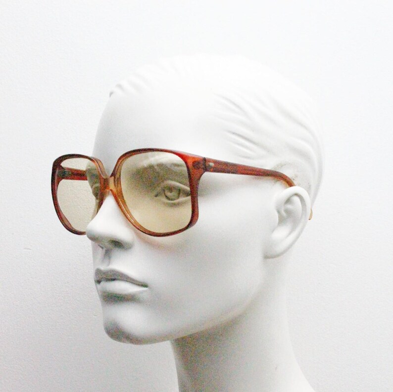 Op de afbeelding: Vintage oversized vierkante bril met een roodbruin montuur en getinte glazen. De bril heeft een klassiek retro-ontwerp, perfect voor een gedurfde fashion statement. De monturen zijn dik en stevig.