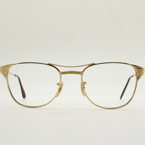 Puede incluir: Gafas de metal doradas con montura rectangular y lentes transparentes.