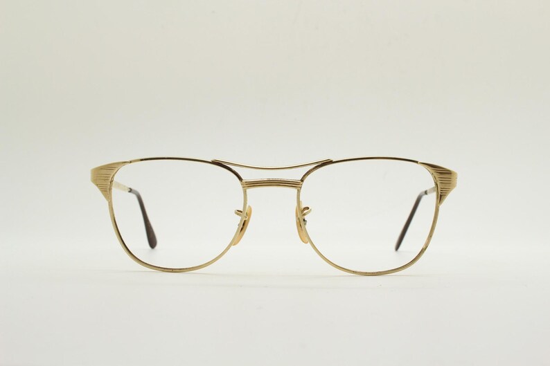 Puede incluir: Gafas de metal doradas con montura rectangular y lentes transparentes.